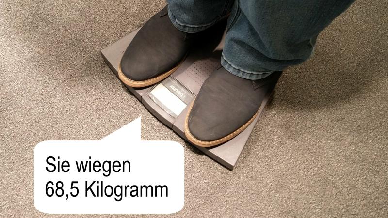 Person auf der Waage, eine Sprechblase zeigt das angesagte Gewicht