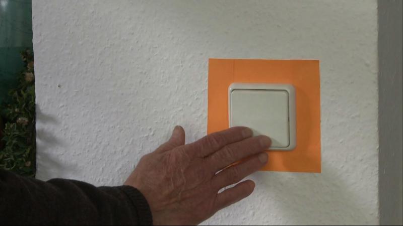 Weißer Lichtschalter mit farbigem Klebeband umgerahmt