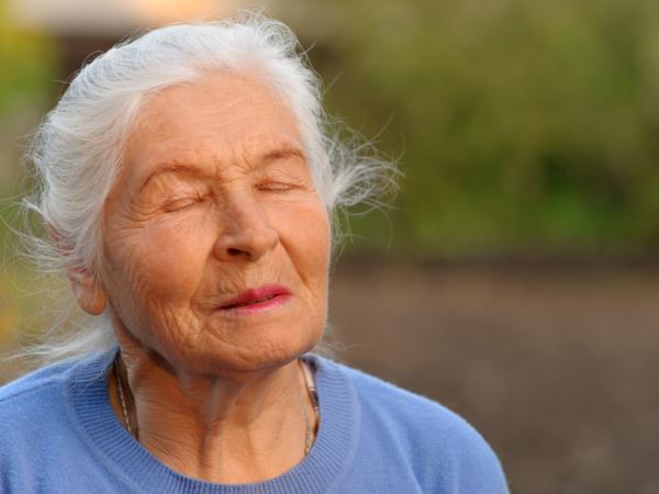Ältere Dame mit geschlossenen Augen in sich ruhend
