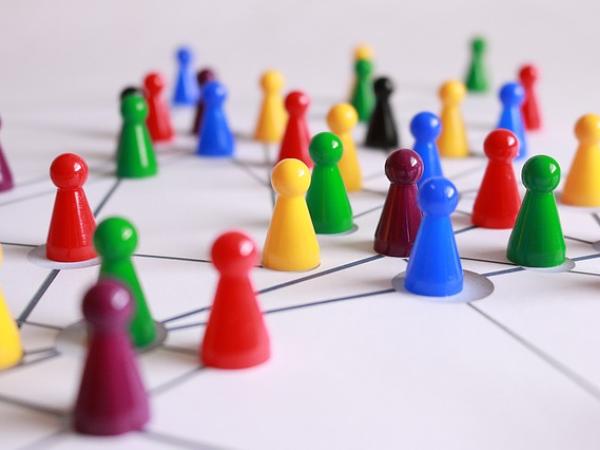 Vernetzungssymbolik: Verschiedenfarbige Spielfiguren gehen Linien entlang und treffen aufeinander