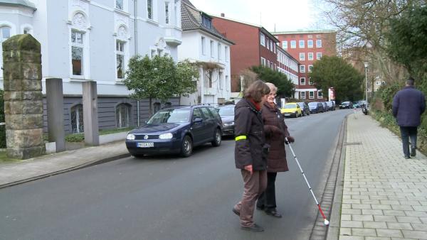 Überqueren einer Straße mit einem Blindenlangstock 
